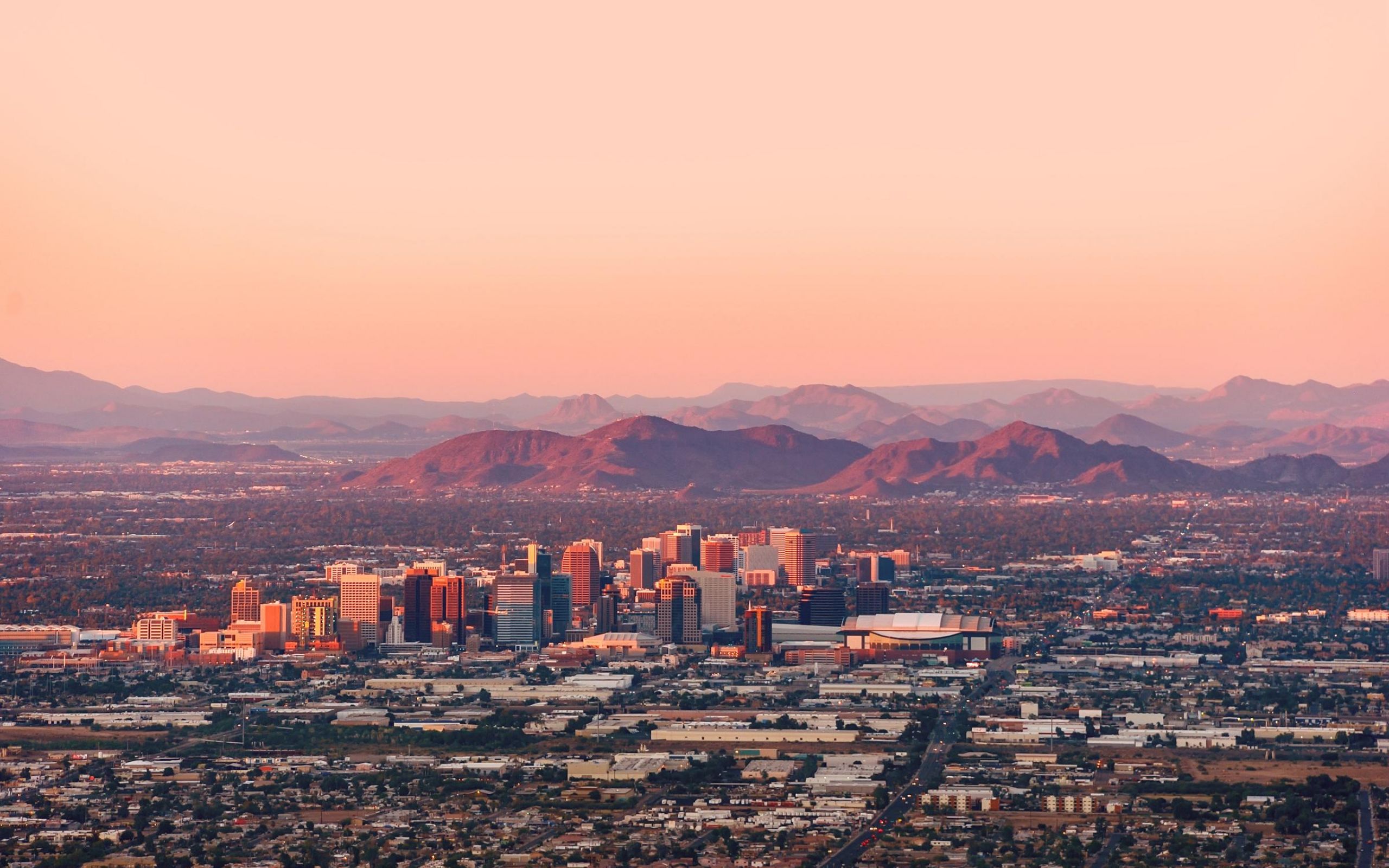 Downtown Phoenix at sunset with mountains in the distance.