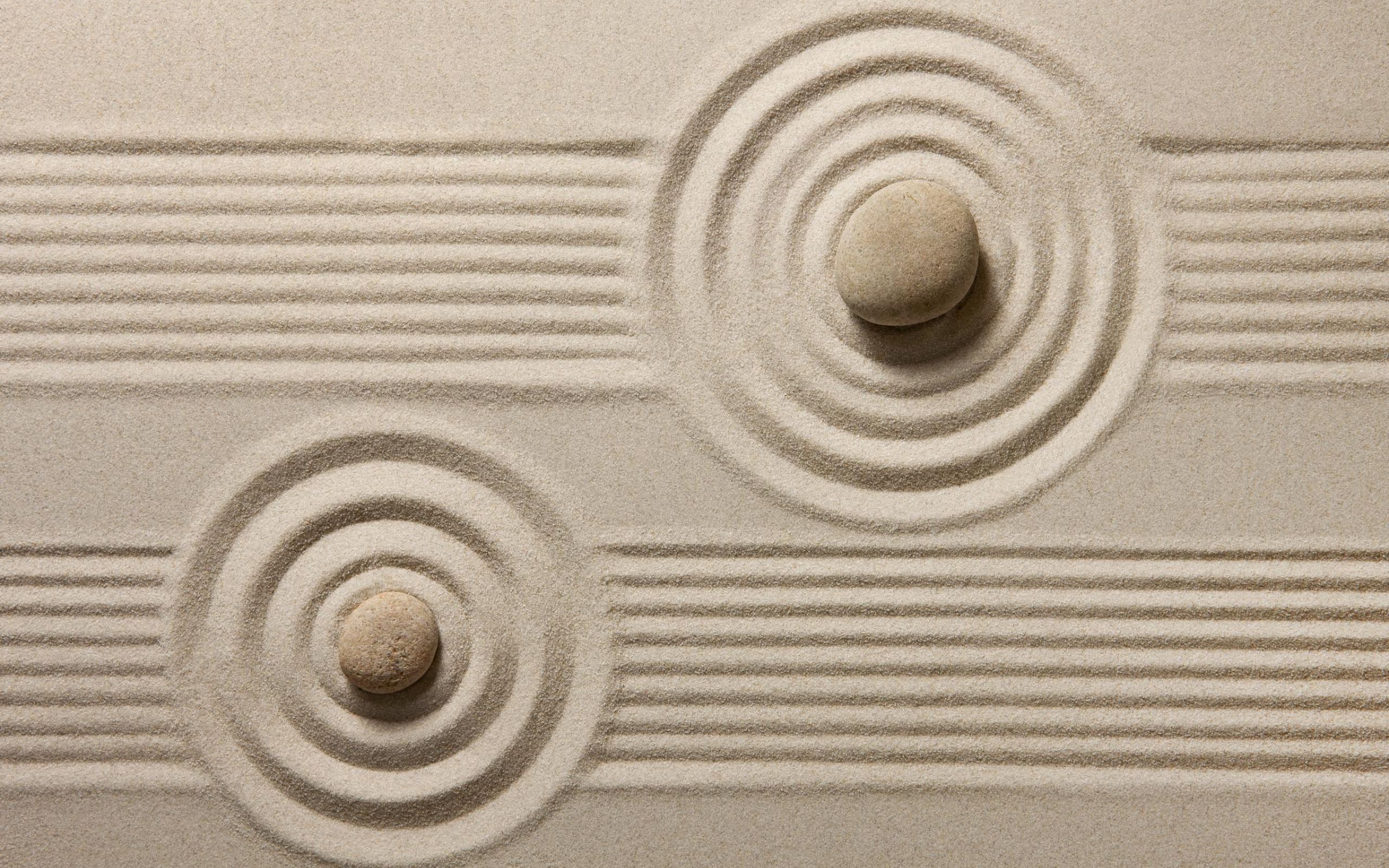 Two round stones resting in a pattern of raked sand.