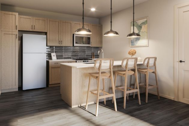 Modern kitchen with light wood cabinets, island, three bar stools, pendant lights, and stainless steel appliances.